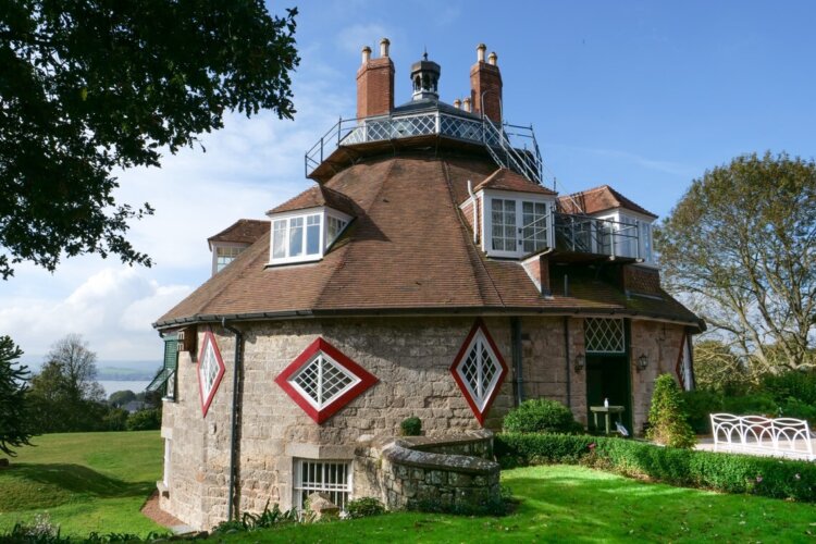 A rounded house with diamond shapes around the belly and a viewing platform at the top, surrounded by green grass.