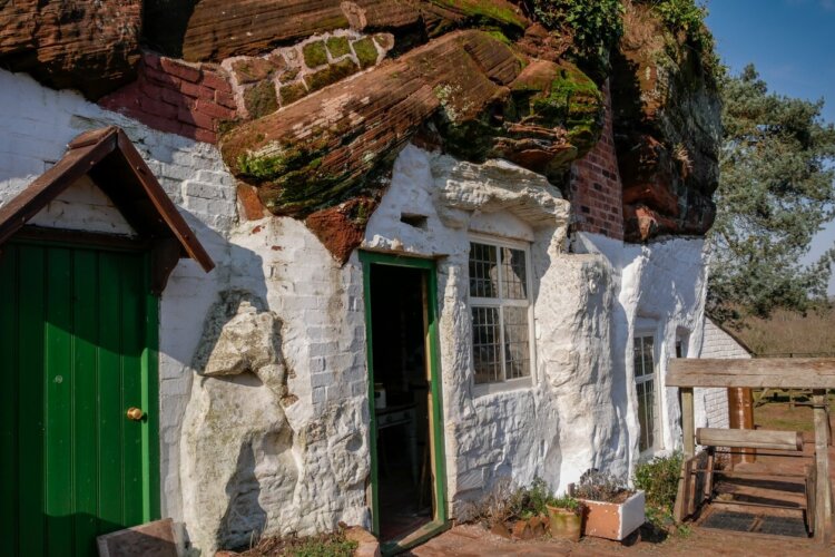 White house with green doors has been build within a rock