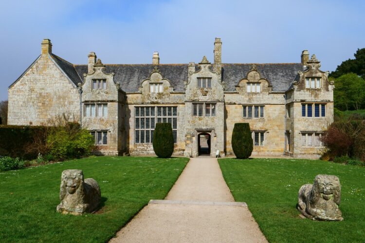 A pair of granite Arundell Lions in the forecourt of a large old house