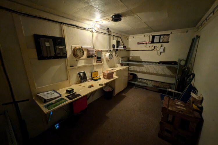 A small dark room with a metal bed and desk.