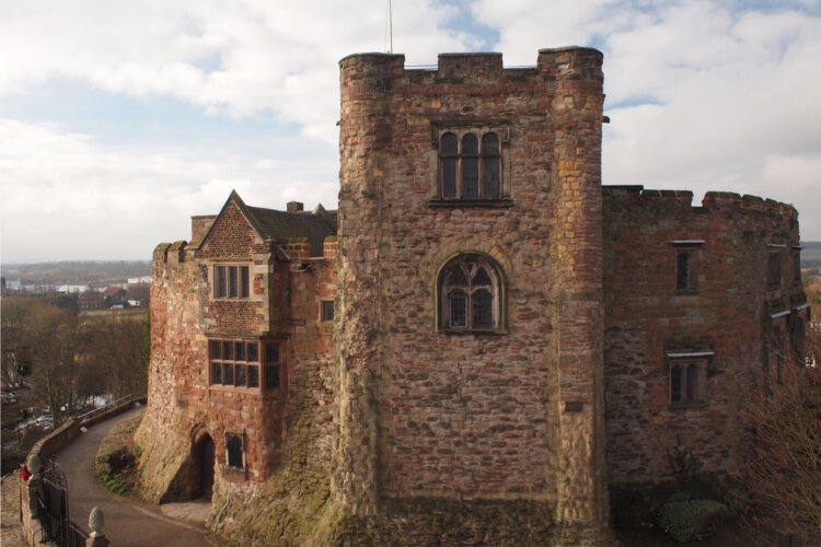 Image of the exterior of a castle tower and wall sitting on top of a mound