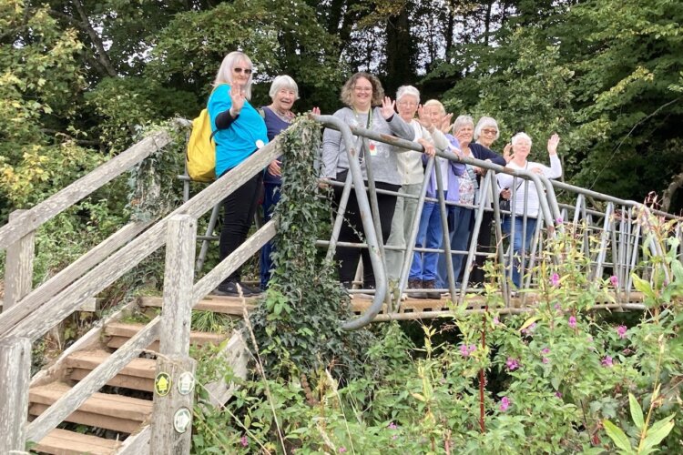 Honiton Carers standing on a bridge waving at the camera at Otterton Mill